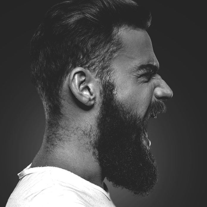 Unleashing his emotions. Side view of furious young bearded man
