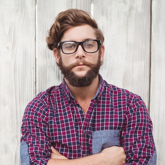 Confident hipster wearing eye glasses with arms crossed selfish