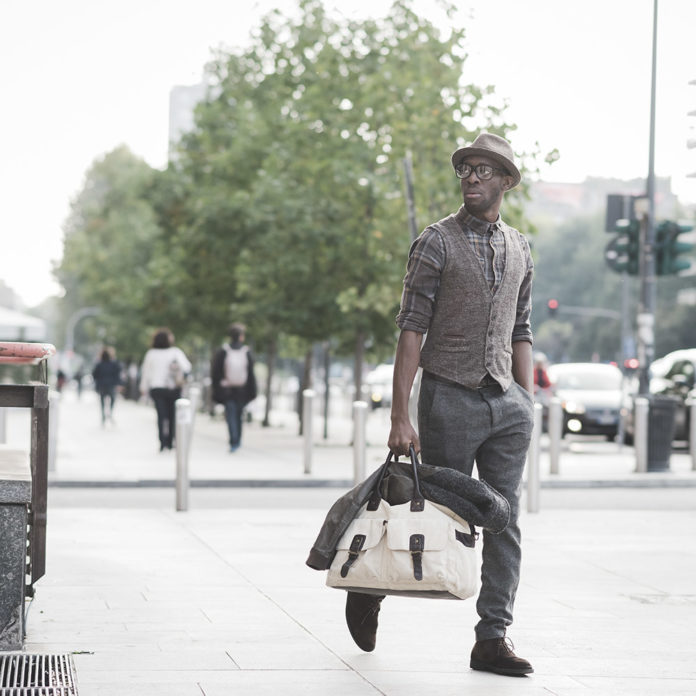 Young handsome afro black man walking in the street of the city, culture